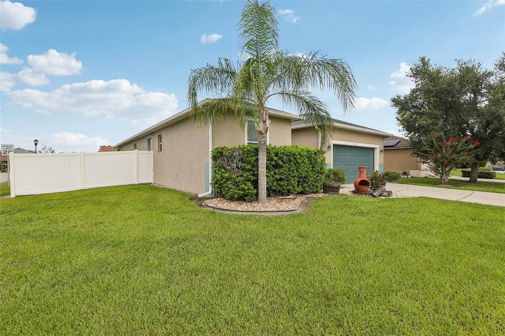 A single-story house with a palm tree, a white fence, and a green garage door — 4362 SUN CENTER ROAD, MULBERRY, FL