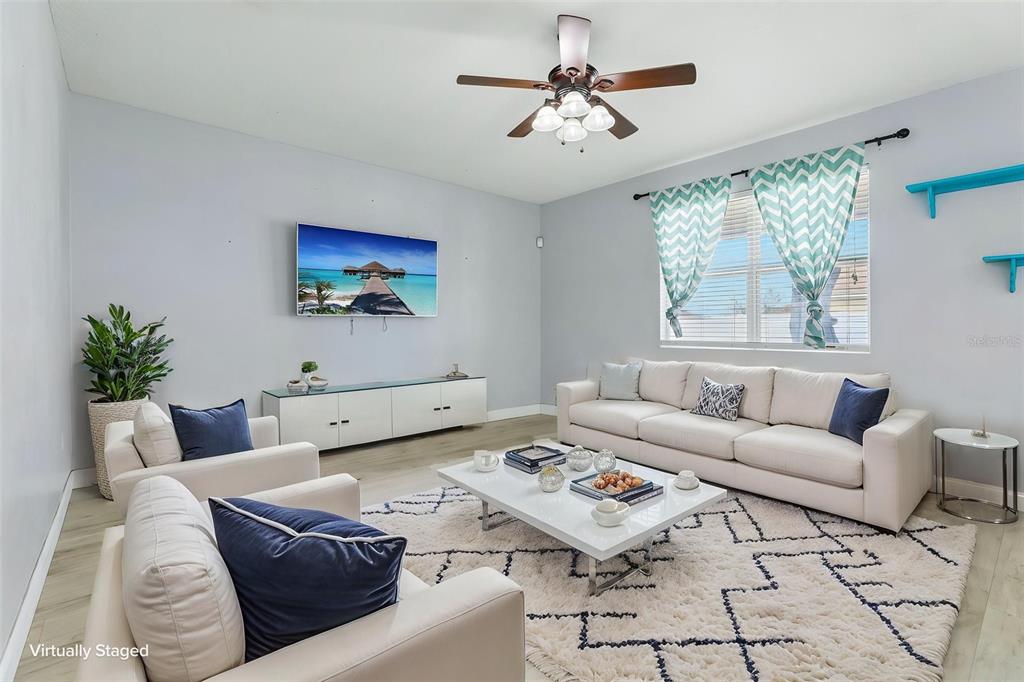 A living room with a white sofa, two armchairs, a coffee table, and a ceiling fan — 4362 SUN CENTER ROAD, MULBERRY, FL