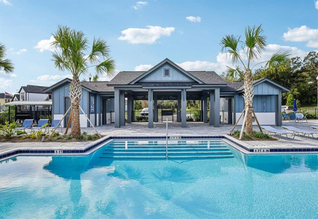 A swimming pool sits in front of a blue clubhouse with a covered patio area — 5813 NATIVE OAK STREET, MOUNT DORA, FL