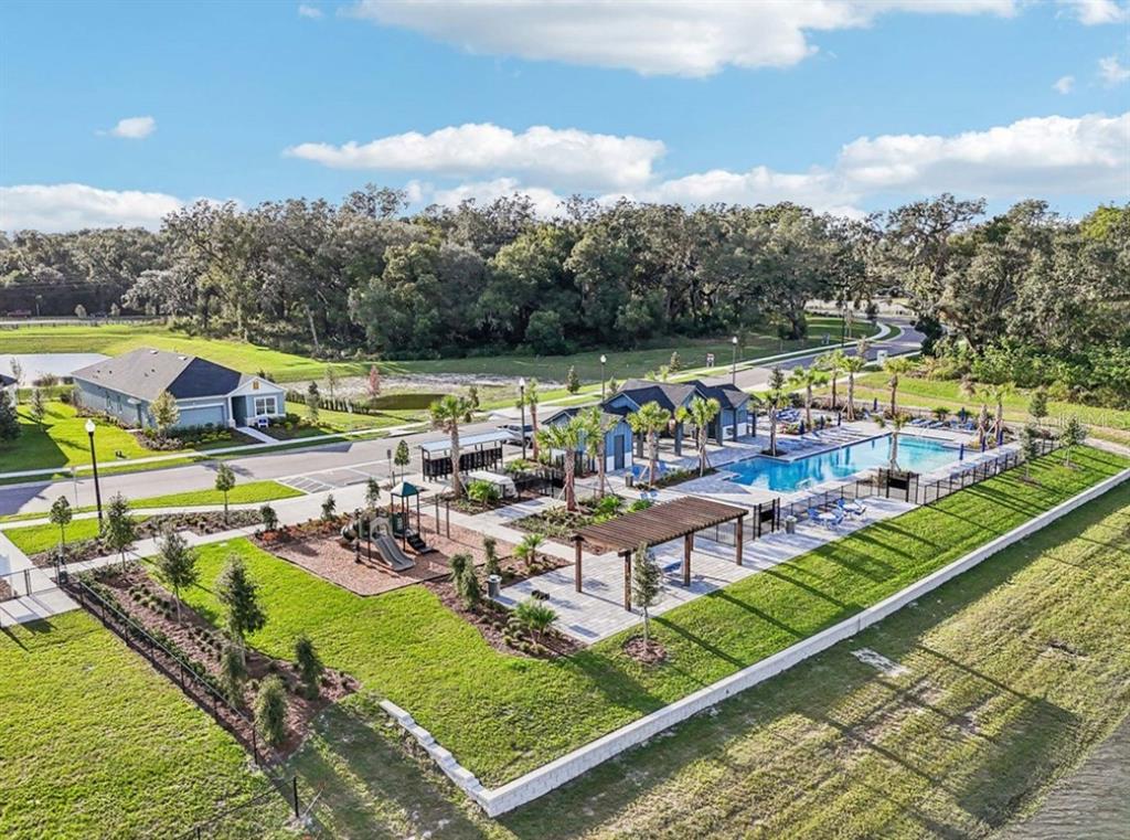 An aerial view of a community pool, playground, and clubhouse surrounded by green space — 5813 NATIVE OAK STREET, MOUNT DORA, FL