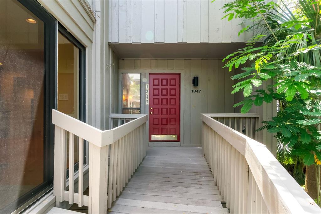 A wooden walkway leads to a red front door with a grid of glass panels — 1347 LANDINGS DRIVE UNIT 6, SARASOTA, FL