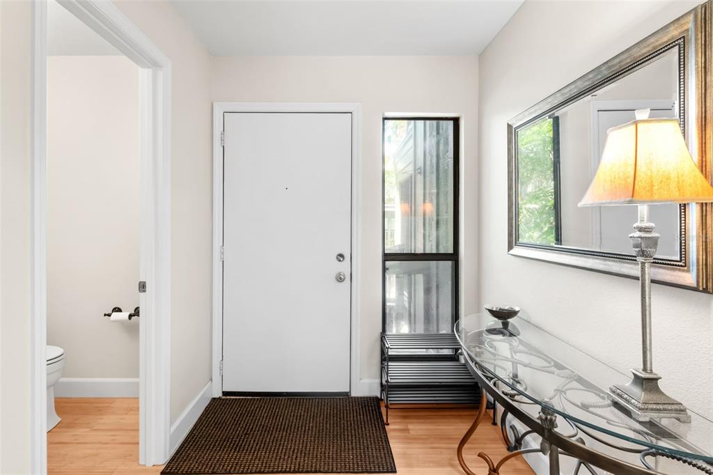 An entryway features a white front door, a glass console table with a lamp, and flooring — 1347 LANDINGS DRIVE UNIT 6, SARASOTA, FL