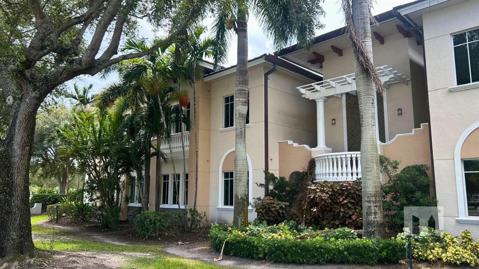 A two-story beige building with palm trees, a white balcony, and a pergola entrance — 160 Congress Park Drive # 111, Delray Beach FL 33445, DELRAY BEACH, FL
