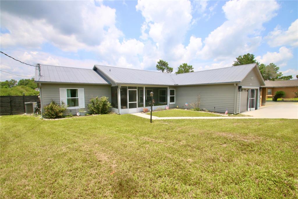 A single-story house with gray horizontal siding, a metal roof, and a screened-in porch — 1812 WHIPPLE DRIVE, DELTONA, FL