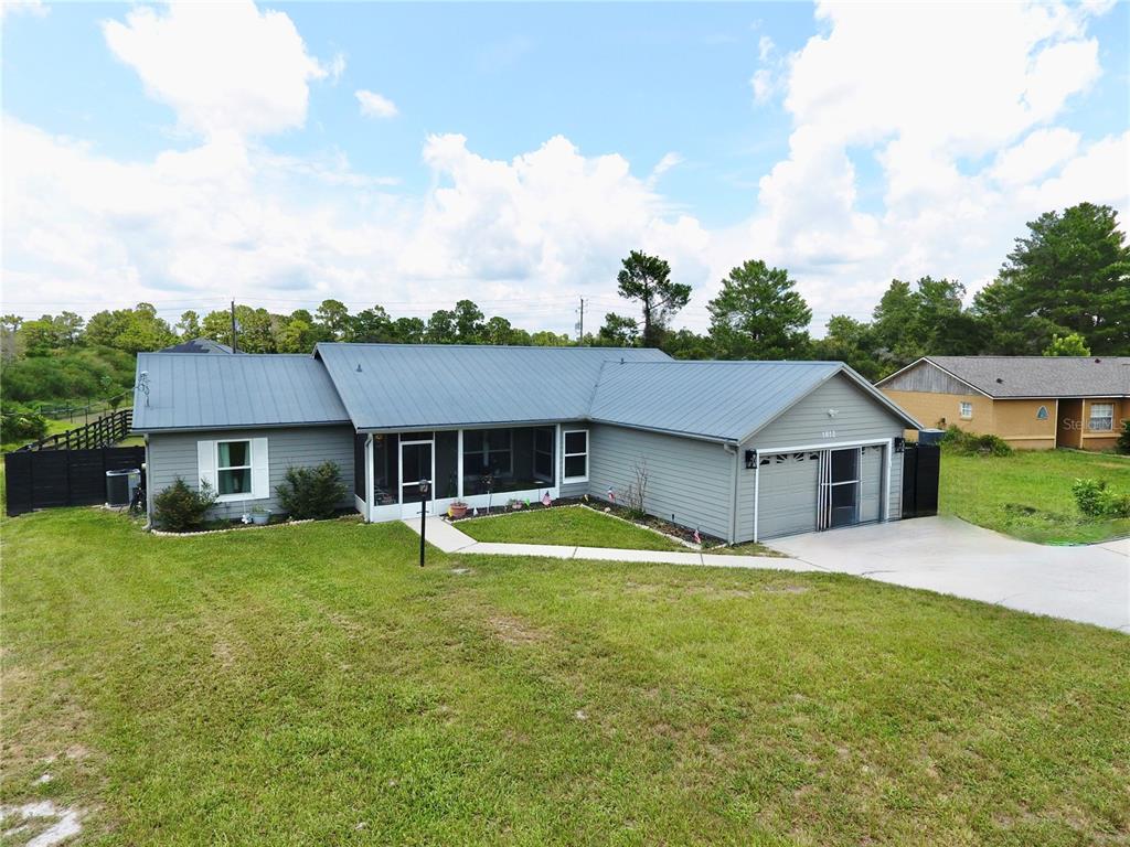 A gray single-story house with a metal roof, attached garage, and a screened front porch — 1812 WHIPPLE DRIVE, DELTONA, FL