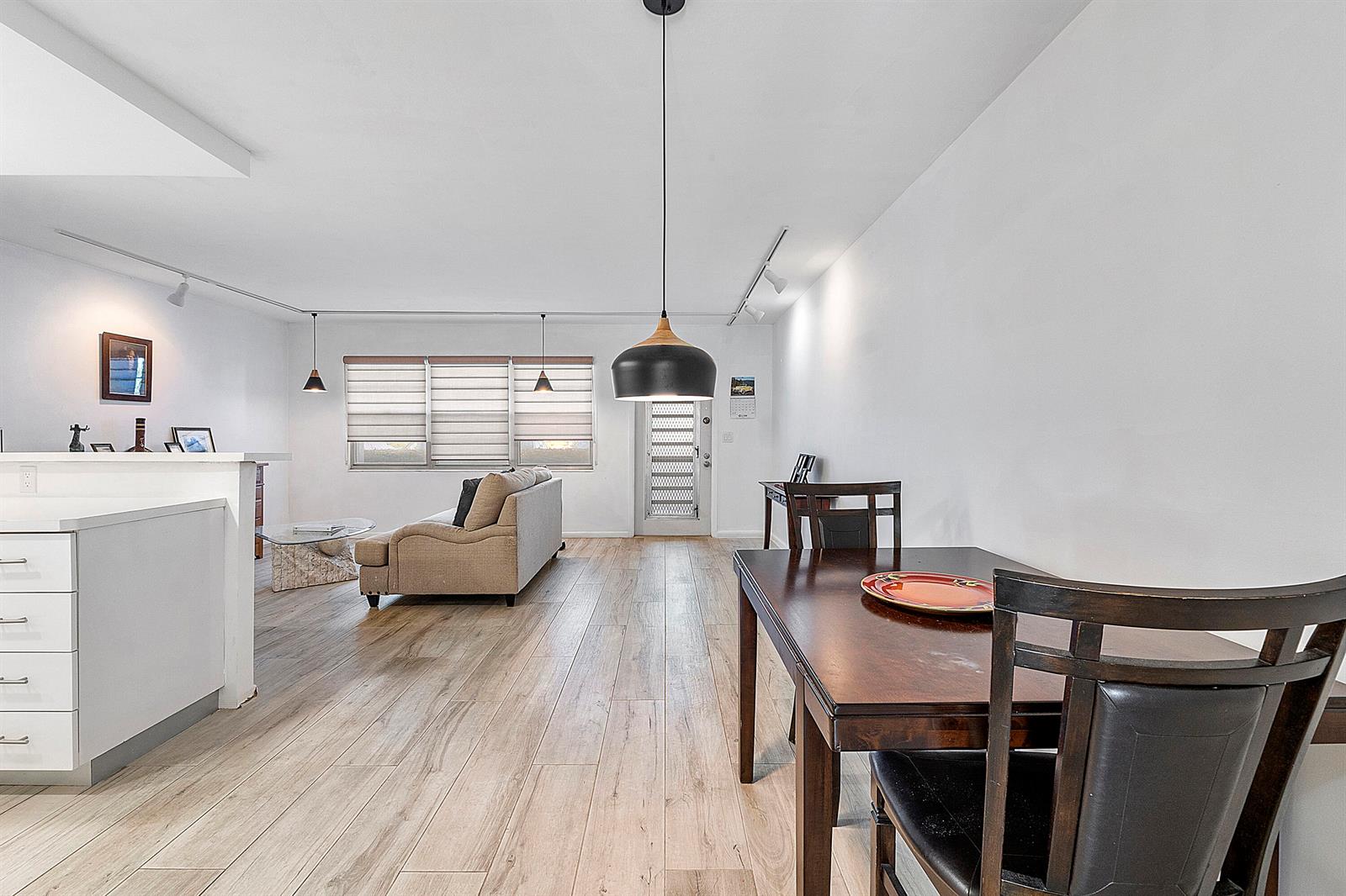 A dining area and living room with light wood flooring and white walls — 1012 Newport G, Deerfield Beach FL 33442, DEERFIELD BEACH, FL