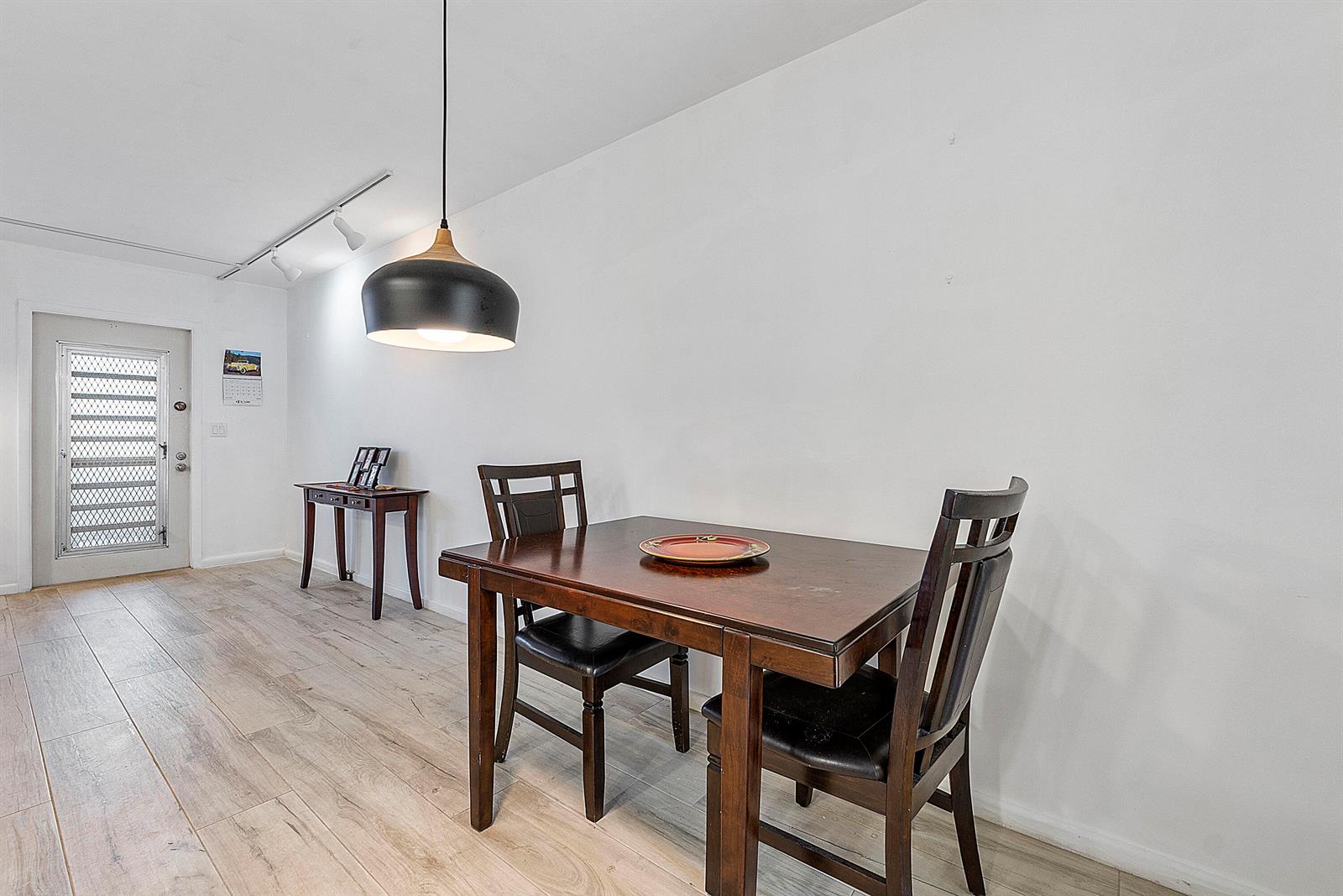 A dining area features a dark wood table, two chairs, and a modern pendant light — 1012 Newport G, Deerfield Beach FL 33442, DEERFIELD BEACH, FL