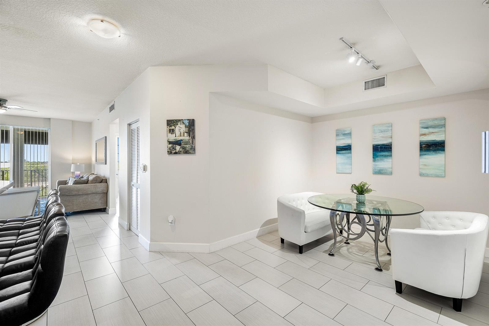 A bright dining area features a glass table, white tufted chairs, and light tile flooring — 255 NE 3rd Avenue # 2503, Delray Beach FL 33444, DELRAY BEACH, FL