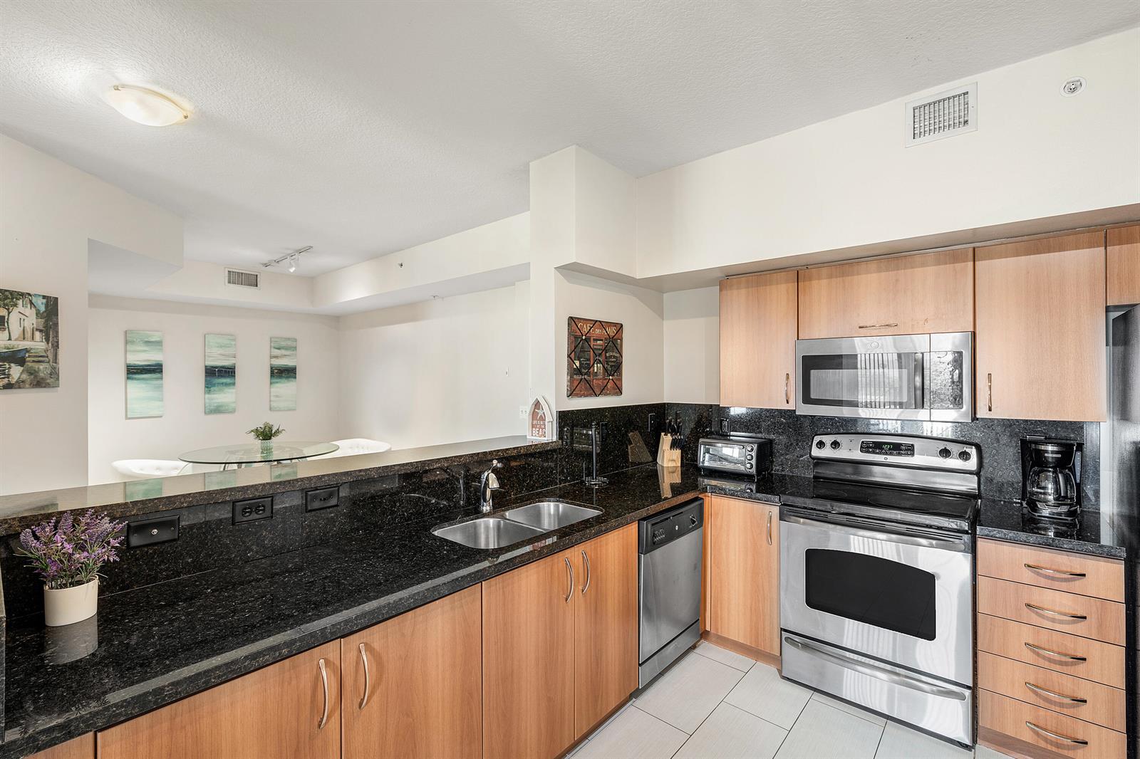 A kitchen features light wood cabinets, black granite countertops, and stainless steel appliances — 255 NE 3rd Avenue # 2503, Delray Beach FL 33444, DELRAY BEACH, FL