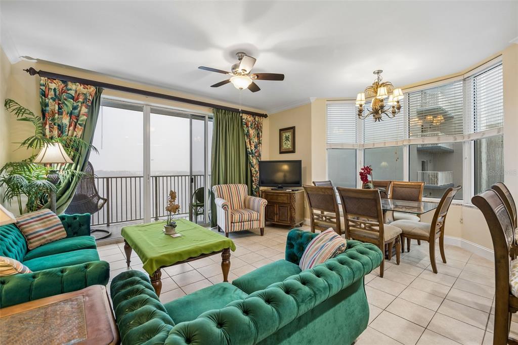A living and dining area features green tufted sofas, a glass table, and a balcony view — 13415 BLUE HERON BEACH DRIVE UNIT 610, ORLANDO, FL