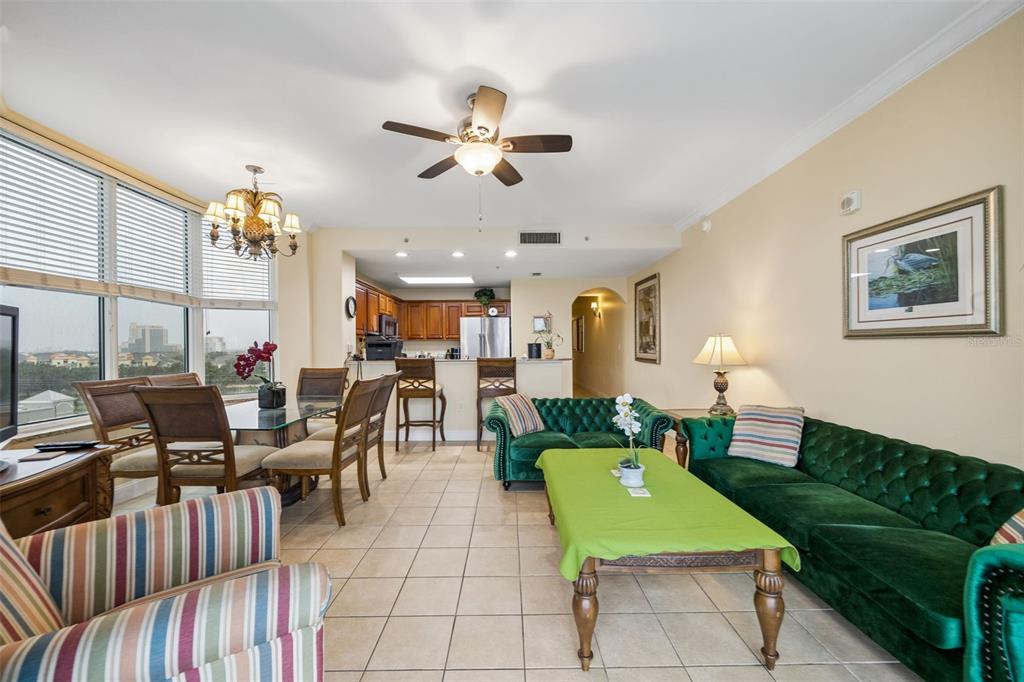 An open-concept living and dining area features green tufted sofas, tile flooring, and a kitchen — 13415 BLUE HERON BEACH DRIVE UNIT 610, ORLANDO, FL