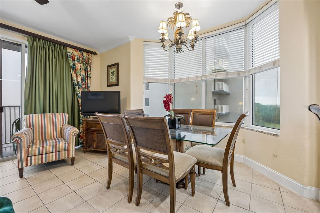 A dining area features a glass-topped table, wooden chairs, a chandelier, and large bay windows — 13415 BLUE HERON BEACH DRIVE UNIT 610, ORLANDO, FL
