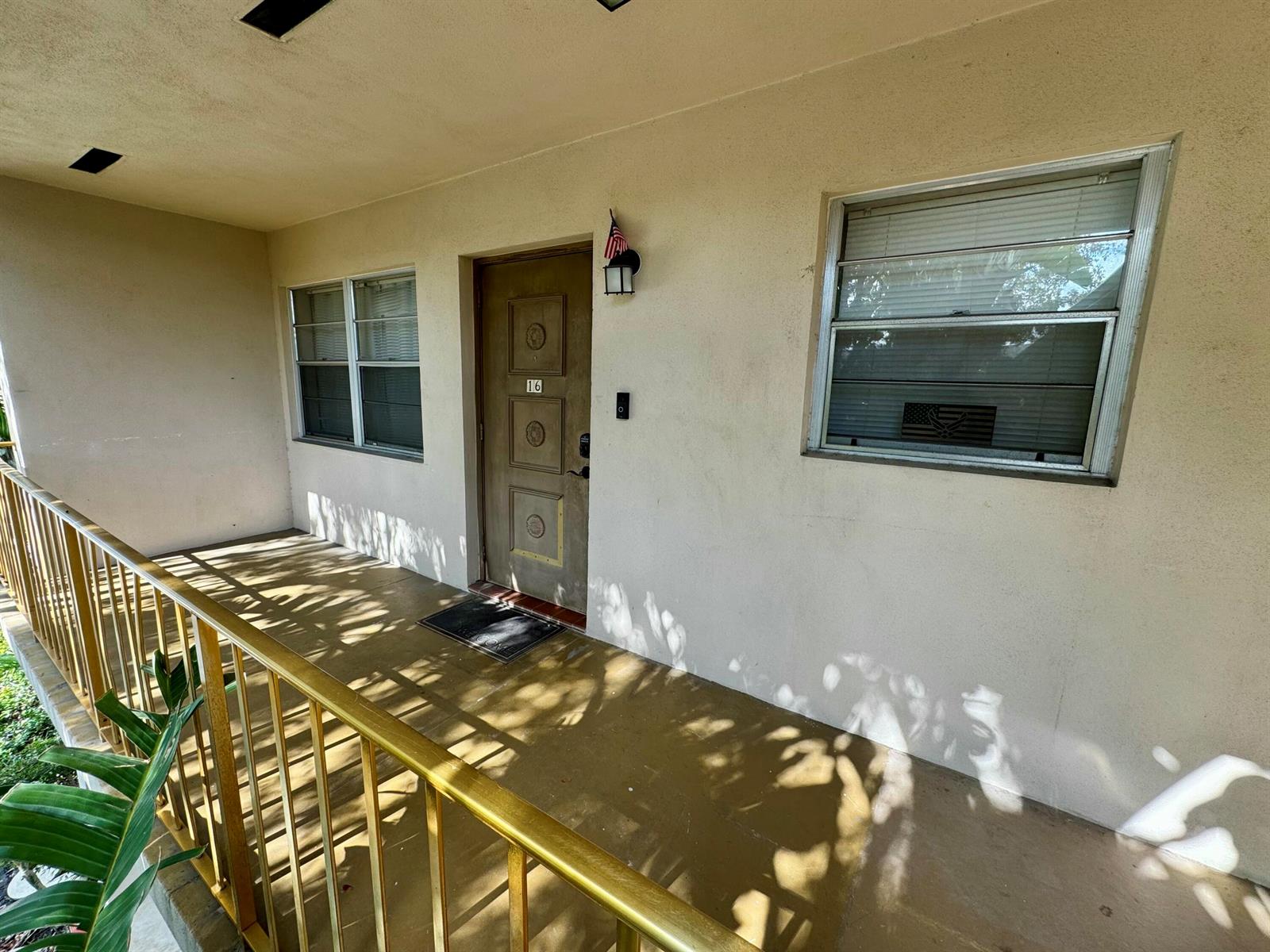 An exterior view of a building entrance with a brown door, windows, and metal railing — 30 S J Street # 16, FL 33460, FL