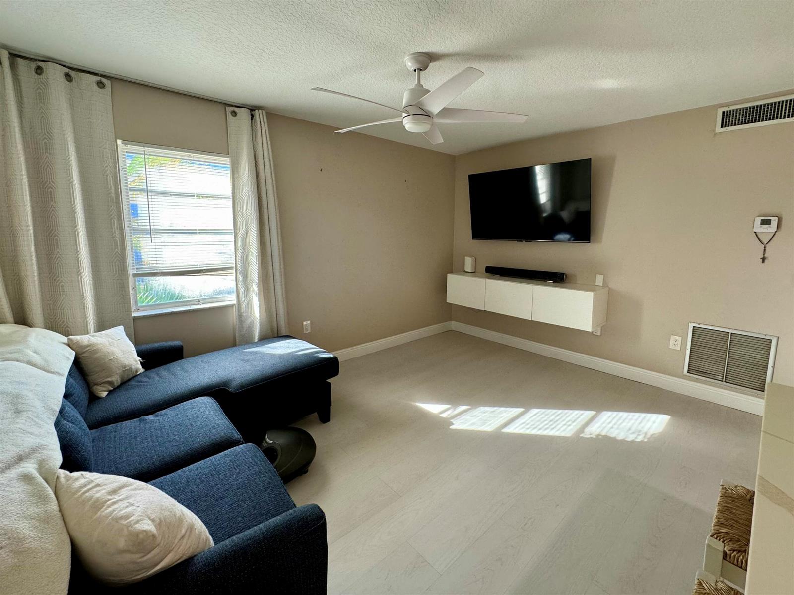 A living room features a blue sectional sofa, a wall-mounted television, and light-colored flooring — 30 S J Street # 16, FL 33460, FL