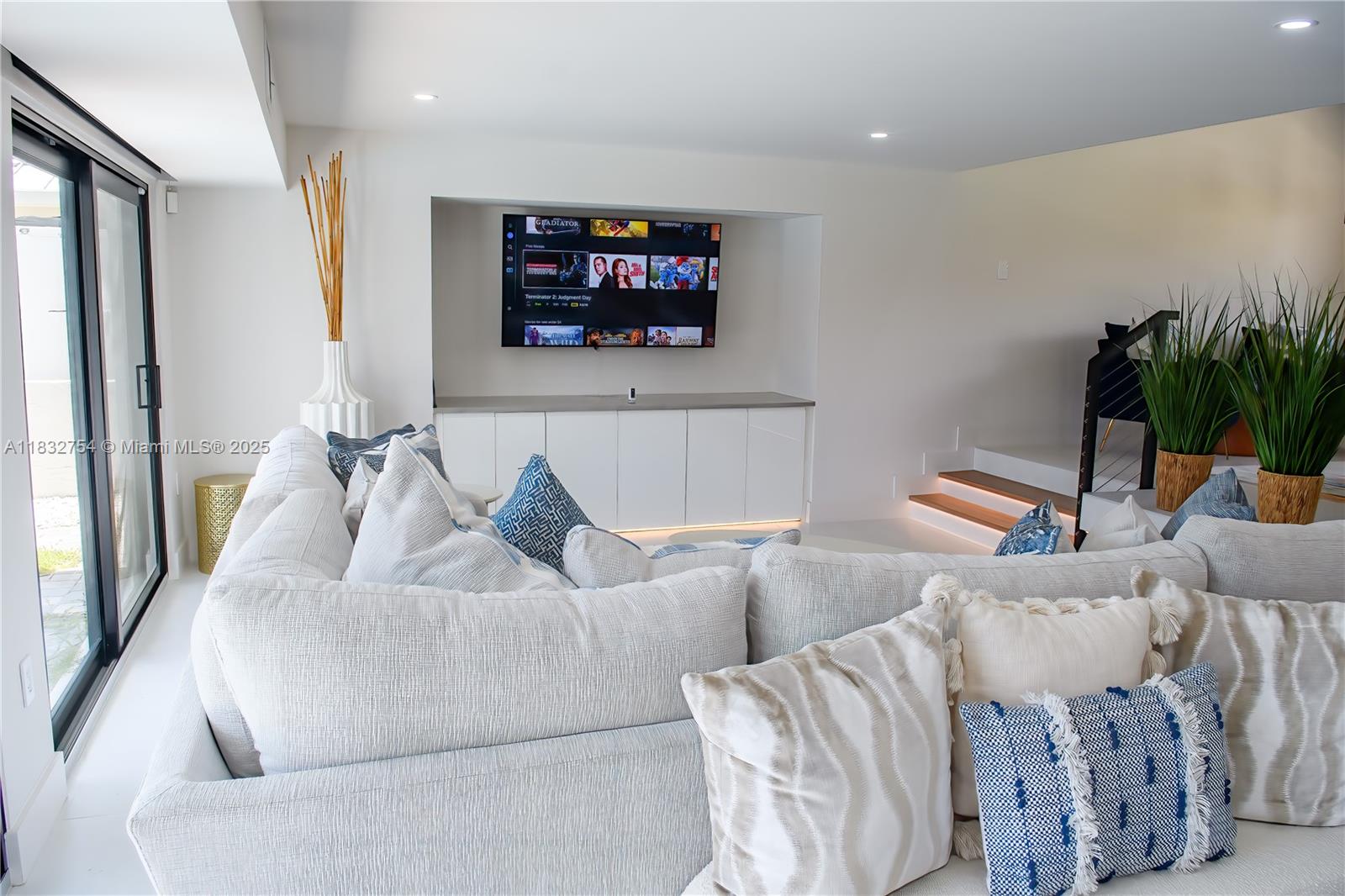 A modern living room features a large sectional sofa, a wall-mounted television, and recessed lighting — 1240 NE 27th Ter, Pompano Beach FL 33062, POMPANO BEACH, FL