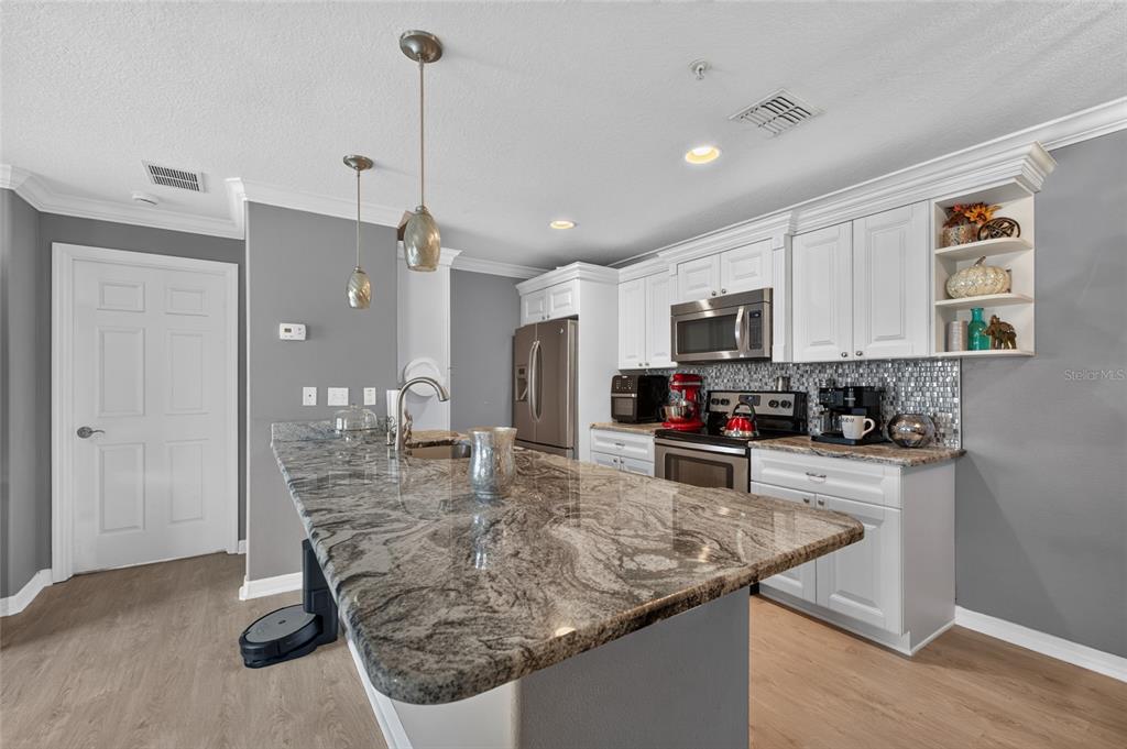 A kitchen features white cabinets, granite countertops, a large island, and stainless steel appliances — 6420 BANYAN BOULEVARD UNIT 201, NEW PORT RICHEY, FL