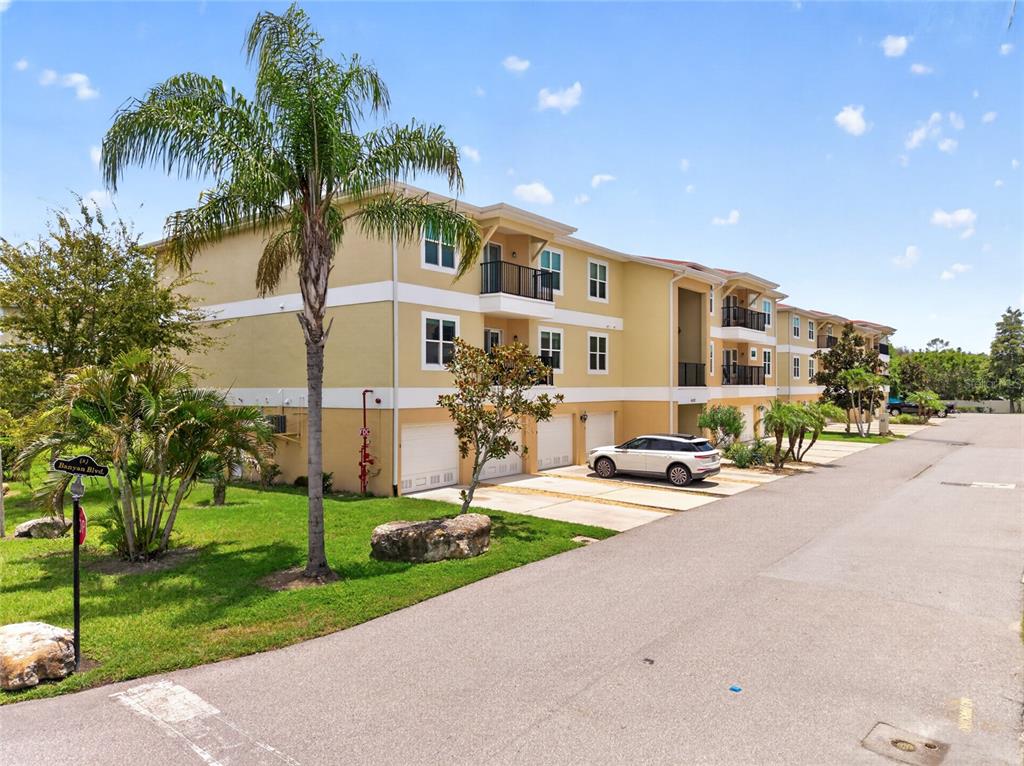 A three-story apartment building with attached garages and a palm tree in the foreground — 6420 BANYAN BOULEVARD UNIT 201, NEW PORT RICHEY, FL