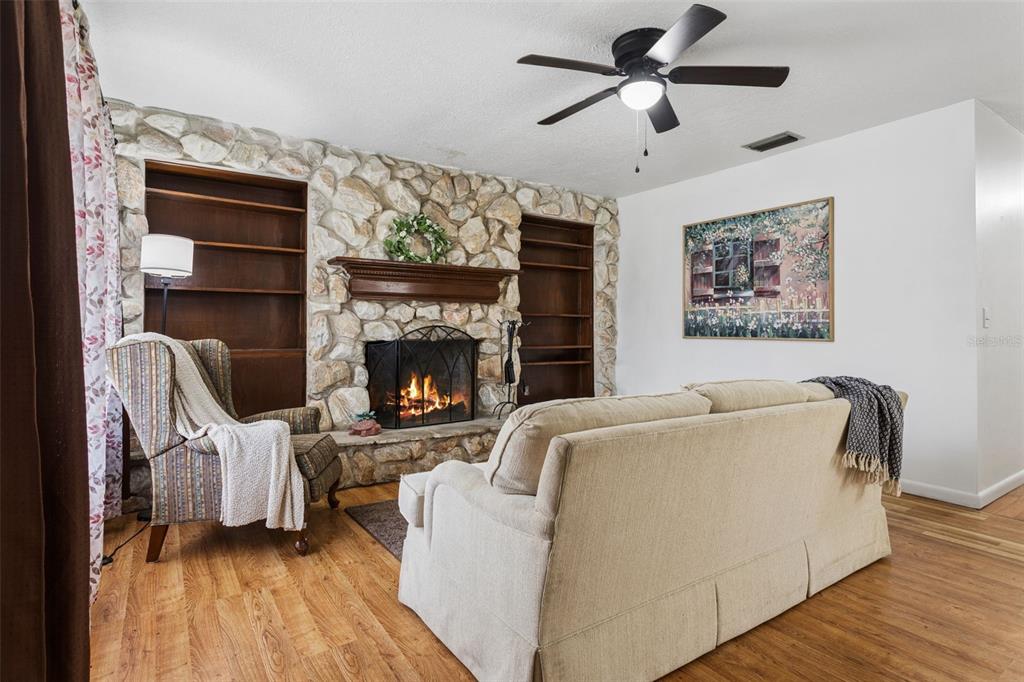 A living room features a stone fireplace, built-in wooden shelves, and a ceiling fan — 8303 TEMPLE PARK DRIVE, TAMPA, FL