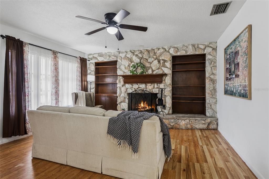 A living room features a stone fireplace, built-in wooden bookshelves, and a beige sofa — 8303 TEMPLE PARK DRIVE, TAMPA, FL