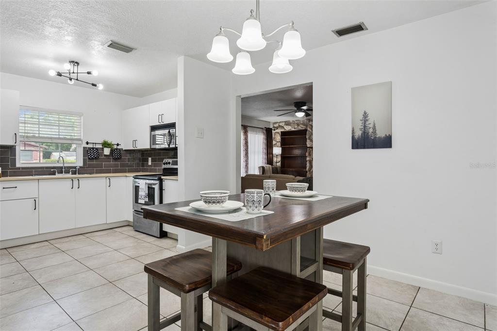 A kitchen and dining area featuring white cabinets, tile flooring, and a wooden table — 8303 TEMPLE PARK DRIVE, TAMPA, FL