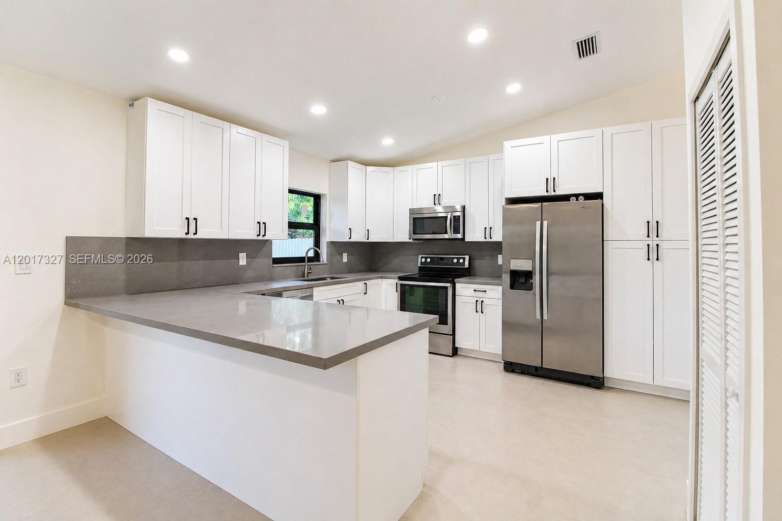 A modern kitchen features white cabinets, gray countertops, and stainless steel appliances — 10088 SW 143rd Ct, Miami FL 33186, MIAMI, FL
