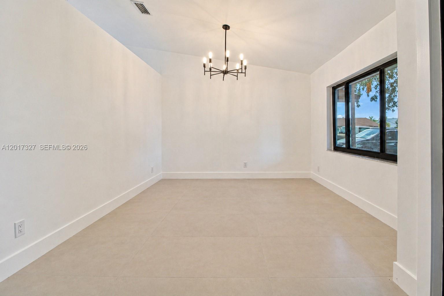 A dining room features white walls, large light-colored floor tiles, and a modern chandelier — 10088 SW 143rd Ct, Miami FL 33186, MIAMI, FL