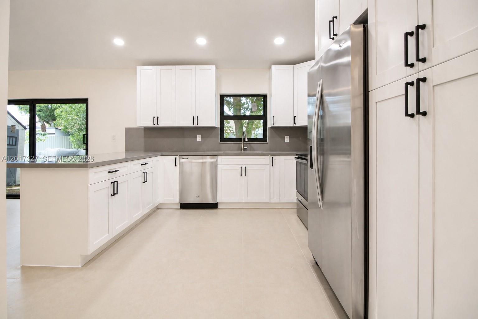 A modern kitchen features white cabinets, stainless steel appliances, and gray countertops — 10088 SW 143rd Ct, Miami FL 33186, MIAMI, FL