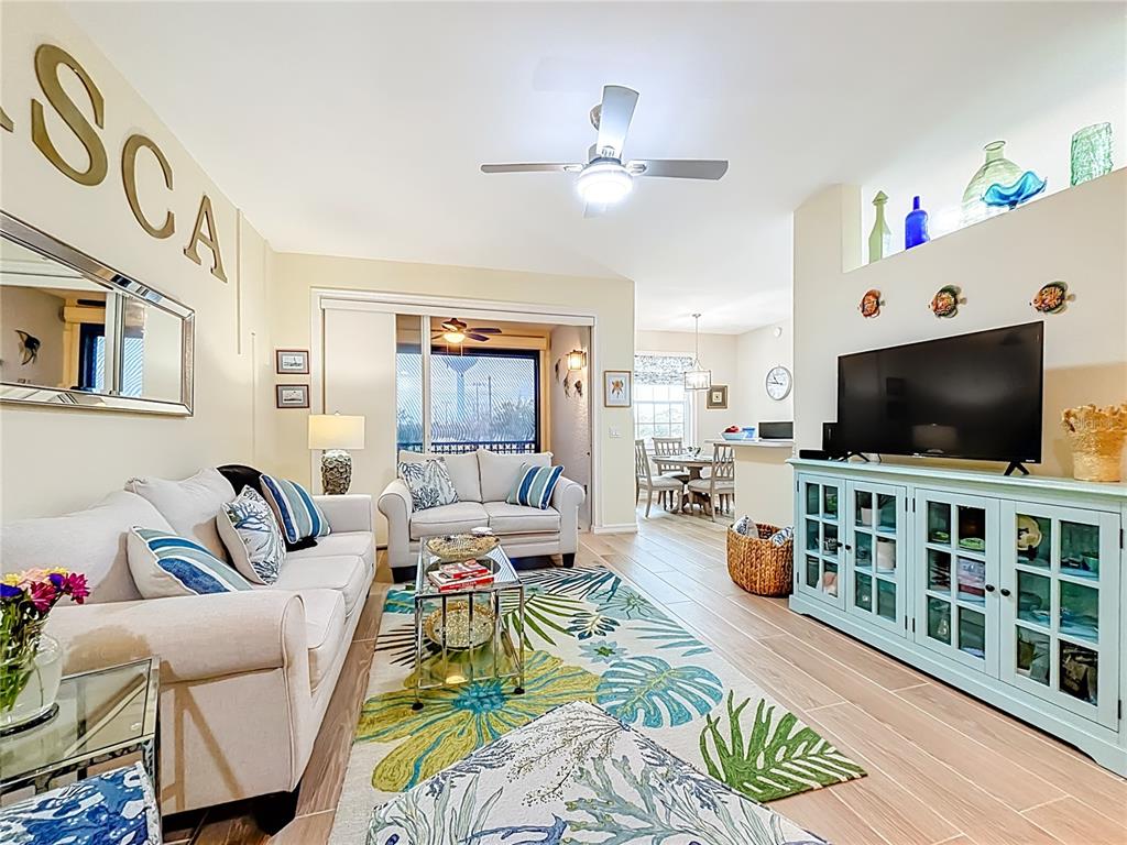 A living room features light-colored sofas, a tropical area rug, and a light blue media console — 960 COOPER STREET UNIT 203, VENICE, FL