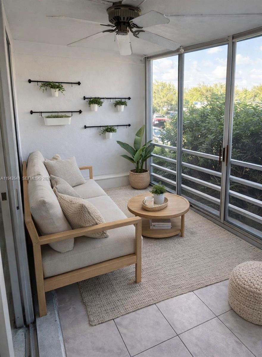 A sunroom features a light-colored sofa, a round wooden coffee table, and wall-mounted planters — 501 E Dania Beach Blvd # 1B, Dania Beach FL 33004, DANIA BEACH, FL