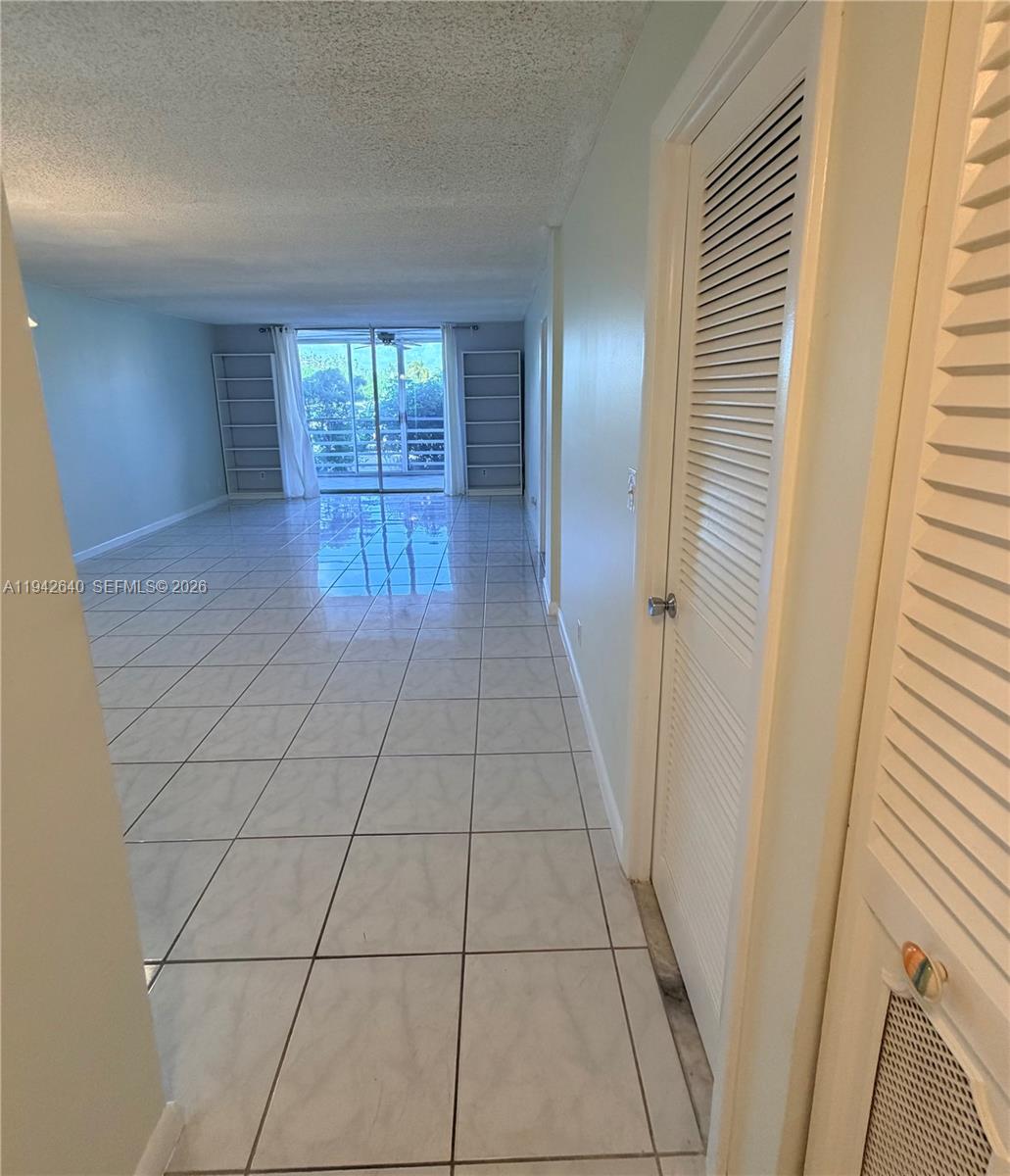 A tiled living area features white walls, built-in shelving, and a sliding glass door — 501 E Dania Beach Blvd # 1B, Dania Beach FL 33004, DANIA BEACH, FL