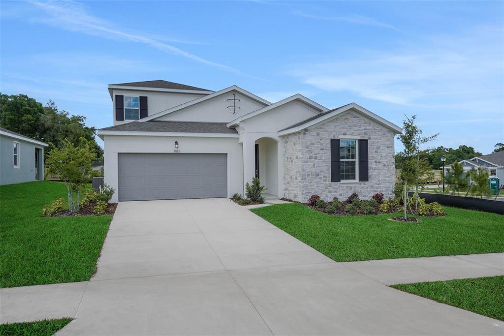 A two-story house with a gray garage, stone facade, and a concrete driveway — 35127 TUSCAN HILL ROAD, DADE CITY, FL