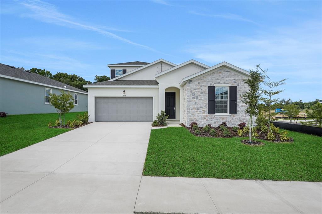 A single-story house with a stone facade, a two-car garage, and a manicured lawn — 35127 TUSCAN HILL ROAD, DADE CITY, FL