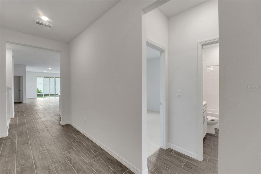 A hallway with wood-look tile flooring leads to a living area and a bathroom — 35127 TUSCAN HILL ROAD, DADE CITY, FL