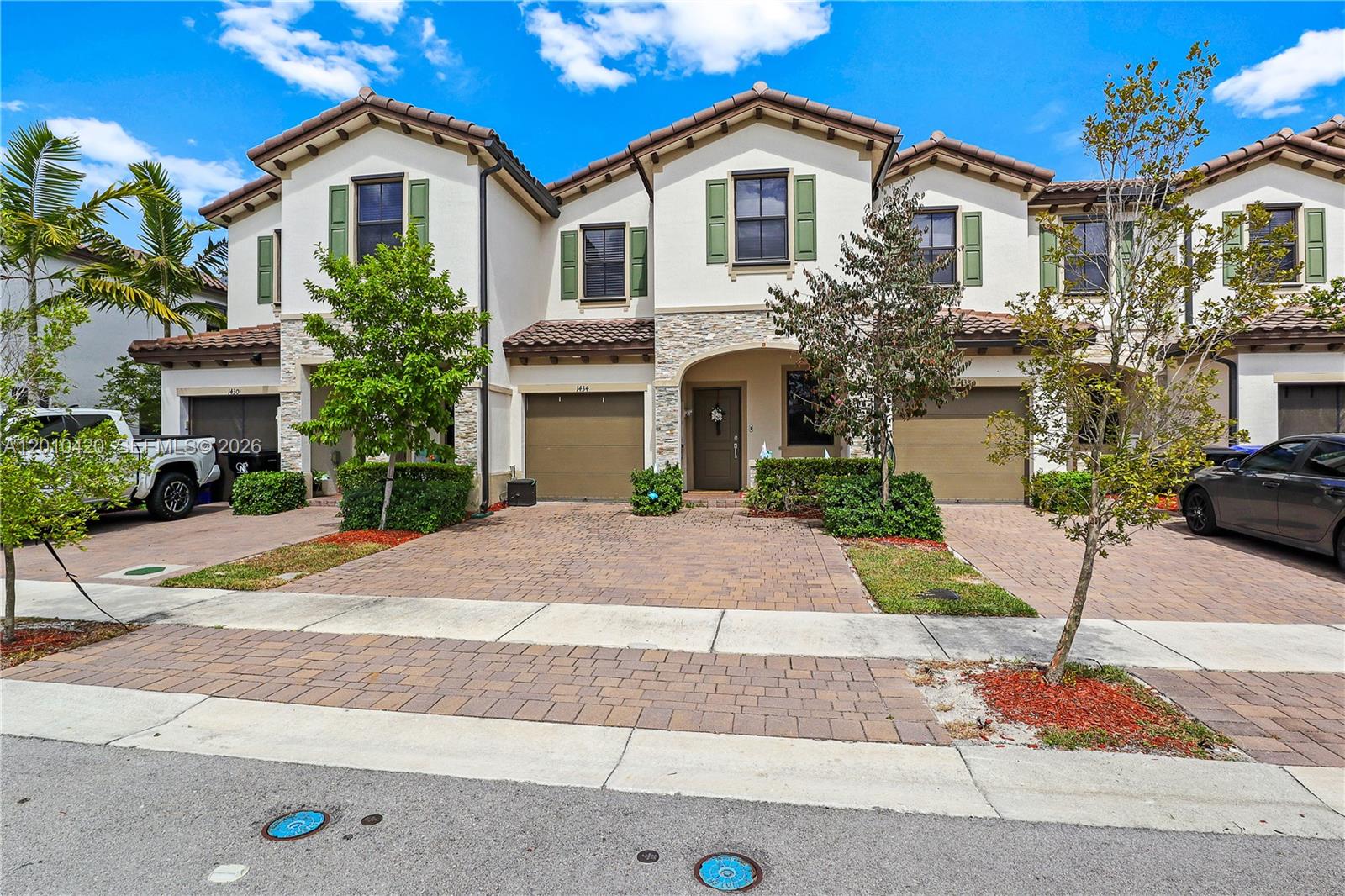 A row of three two-story townhouses features stucco walls, stone accents, and paved driveways — 1434 SW 54th Ave, North Lauderdale FL 33068, NORTH LAUDERDALE, FL