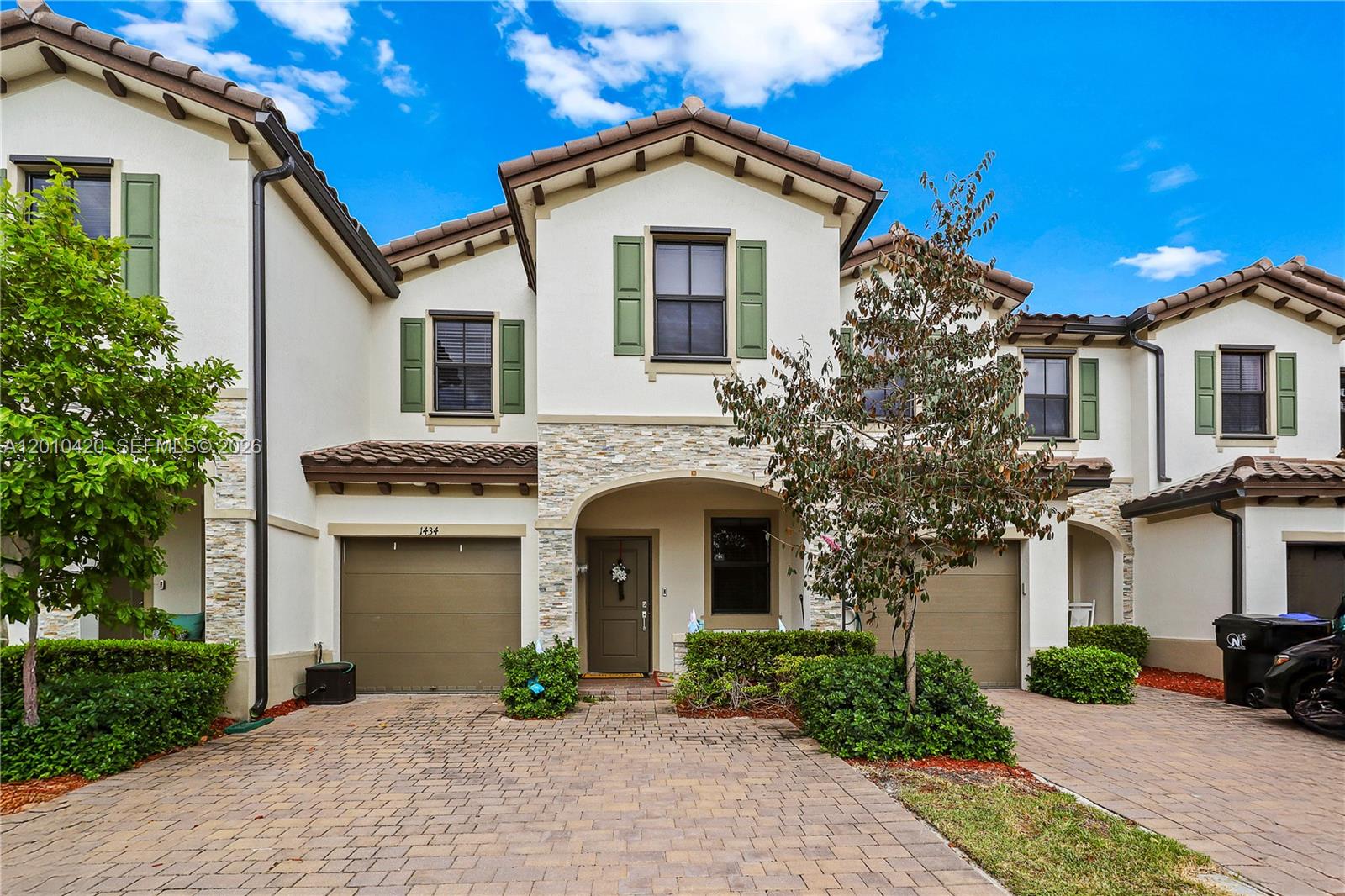 A two-story townhouse with a stone facade, green shutters, and a paved driveway — 1434 SW 54th Ave, North Lauderdale FL 33068, NORTH LAUDERDALE, FL
