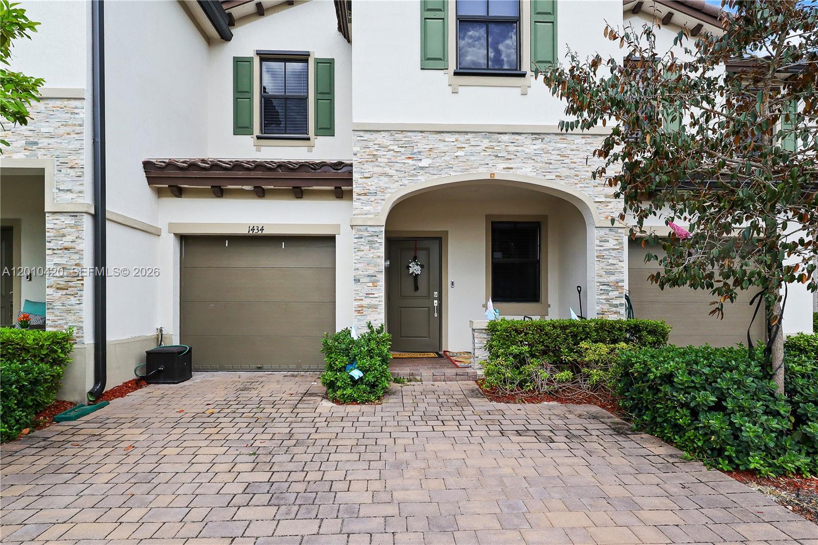 The exterior of a two-story townhouse features a stone facade, green shutters, and a garage — 1434 SW 54th Ave, North Lauderdale FL 33068, NORTH LAUDERDALE, FL