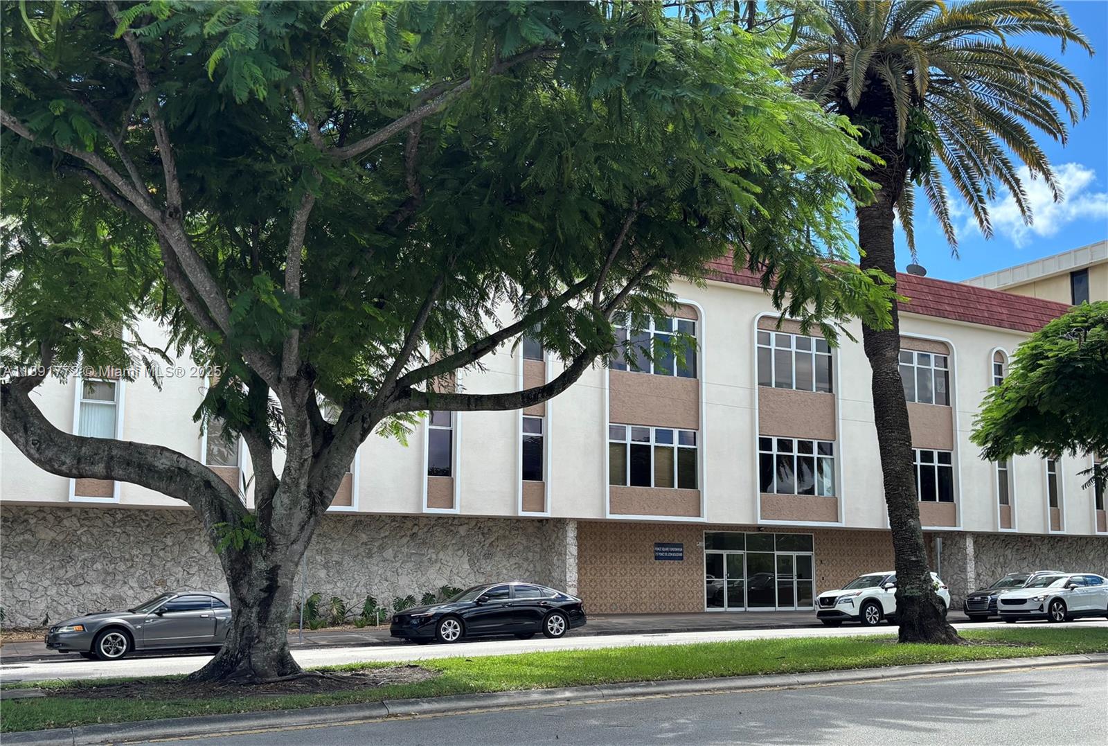 A multi-story building with a stone-textured base, light-colored walls, and large trees in front — 717 Ponce De Leon Blvd # 328, Coral Gables FL 33134, CORAL GABLES, FL