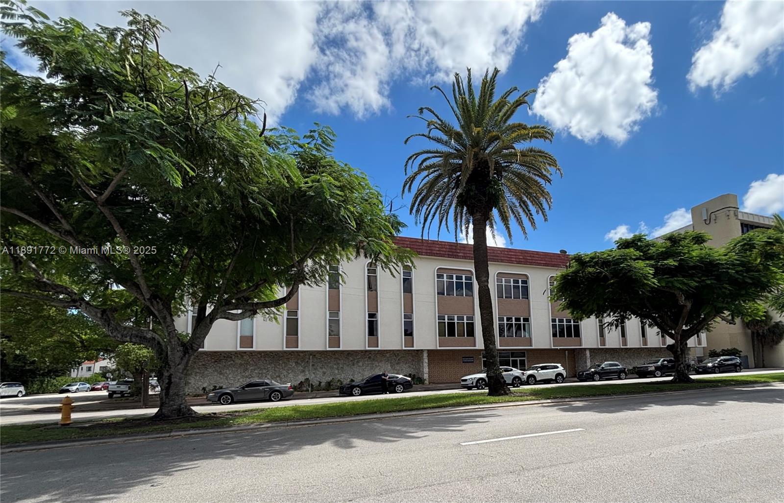 A three-story commercial building with a stone base and palm trees stands beside a road — 717 Ponce De Leon Blvd # 328, Coral Gables FL 33134, CORAL GABLES, FL