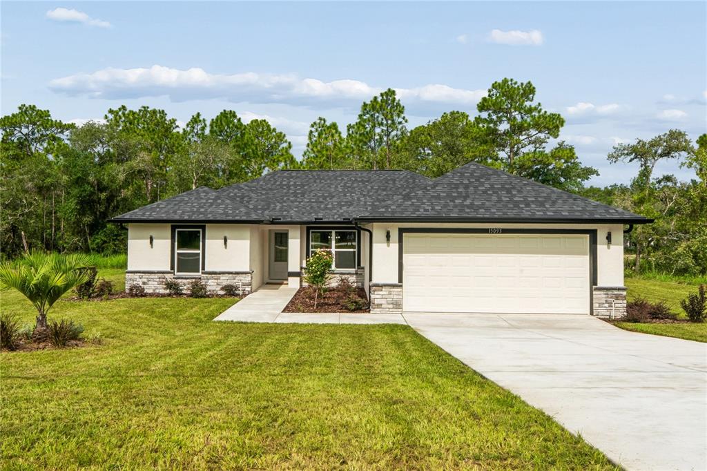A single-story house with a white stucco facade, stone accents, and a two-car garage — 15093 GONZO ROAD, WEEKI WACHEE, FL
