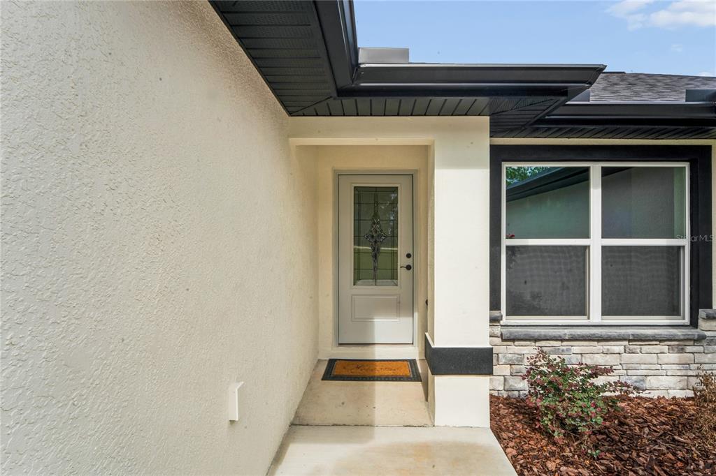 A front entryway features a light-colored door with decorative glass, a concrete porch, and stucco — 15093 GONZO ROAD, WEEKI WACHEE, FL