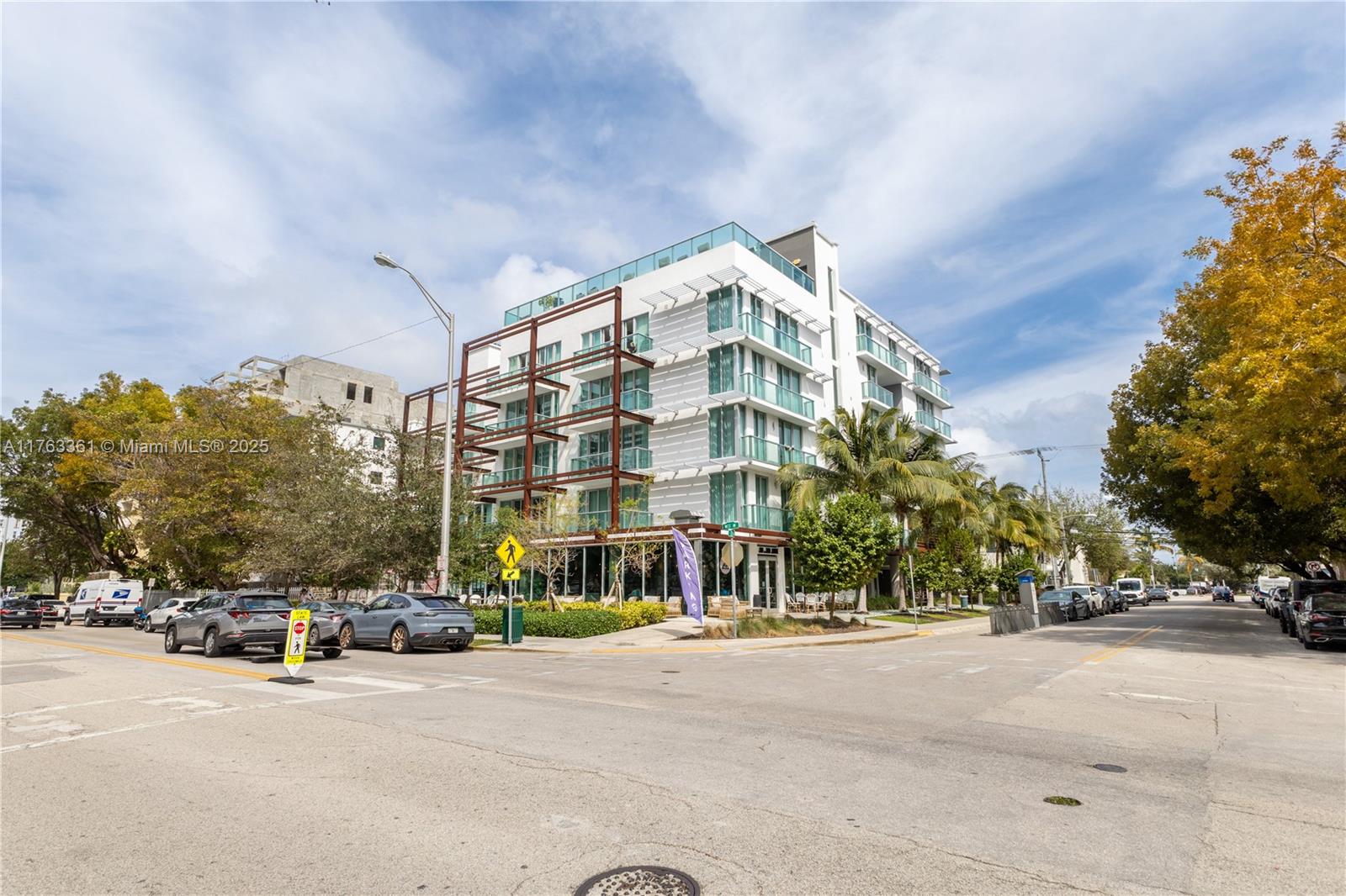 A modern multi-story apartment building stands on a street corner with palm trees nearby — 1215 West Ave # 203, Miami Beach FL 33139, MIAMI BEACH, FL
