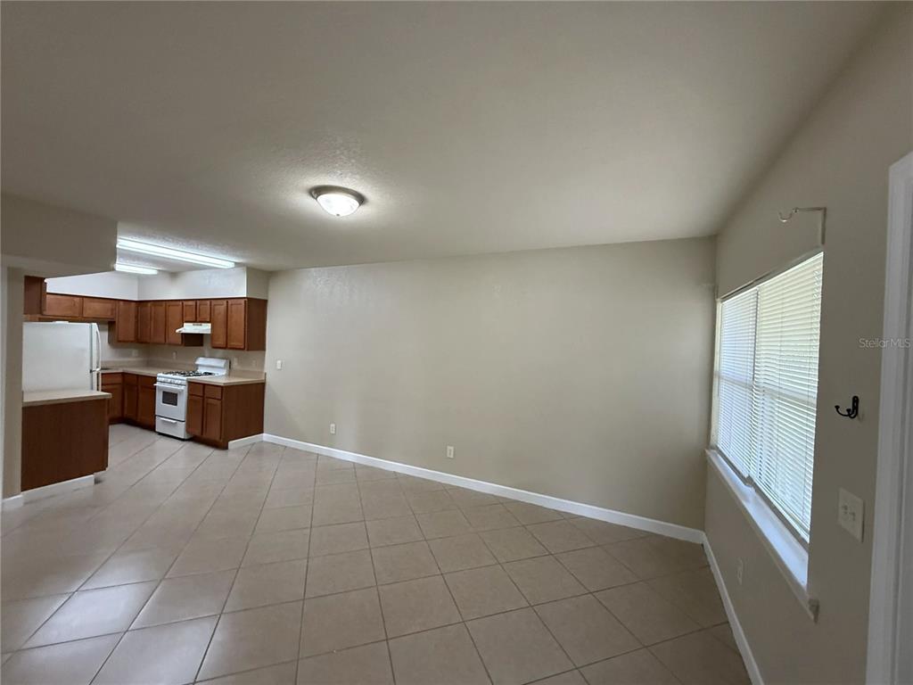 An open-concept kitchen with wood cabinets and tile flooring flows into a living area — 1355 DREW STREET UNIT 101, CLEARWATER, FL