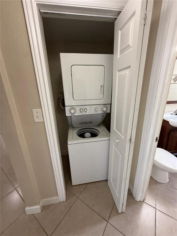 A stacked washer and dryer unit is located inside a small closet in a tiled room — 1355 DREW STREET UNIT 101, CLEARWATER, FL