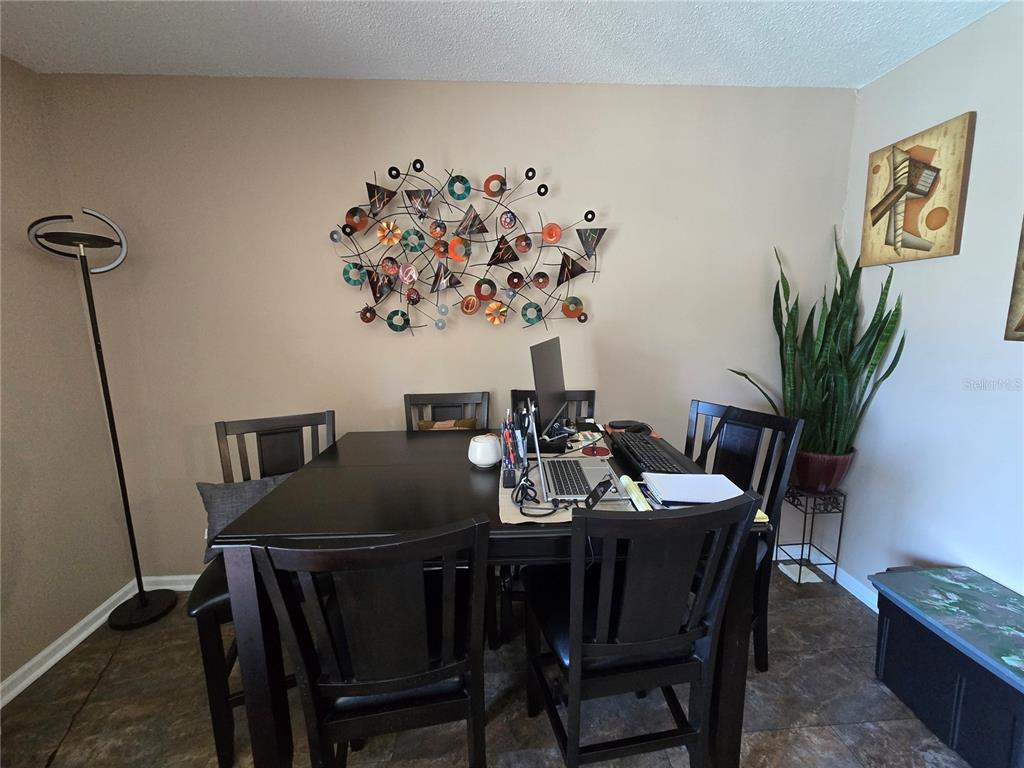 A dining room features a dark wood table, chairs, wall art, and a floor lamp — 6305 NEWTOWN CIRCLE UNIT 5B4, TAMPA, FL