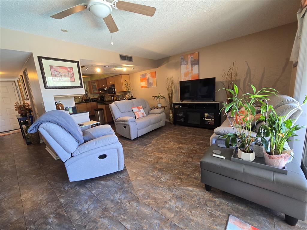 A living room features tile flooring, a ceiling fan, gray furniture, and an open kitchen — 6305 NEWTOWN CIRCLE UNIT 5B4, TAMPA, FL