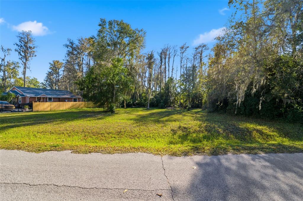 A vacant, grassy residential lot sits next to a house with a wooden fence — 0 MOON LAKE CIRCLE, NEW PORT RICHEY, FL