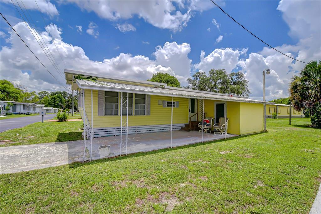 A yellow mobile home with a covered carport and a small front porch — 37344 HAMMOND DRIVE, ZEPHYRHILLS, FL
