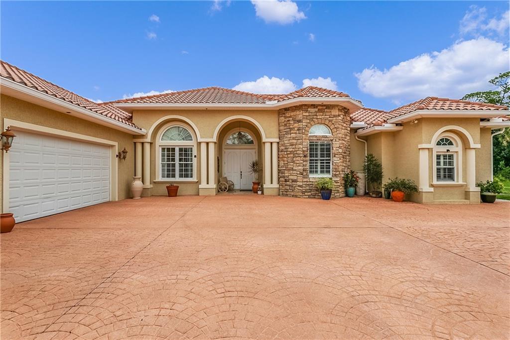 A single-story house with a stone facade, arched windows, and a large stamped concrete driveway — 10750 146th Avenue, Fellsmere FL 32948, FELLSMERE, FL