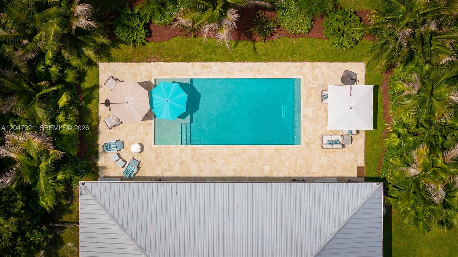 An aerial view shows a rectangular swimming pool surrounded by a stone patio and palm trees — 12127 N 154th Rd N, Jupiter FL 33478, JUPITER, FL