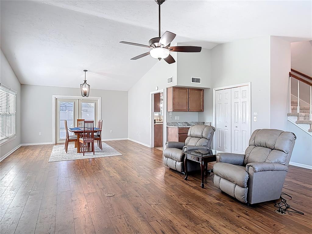 A living and dining area features wood-look flooring, a vaulted ceiling, and two recliners — 1807 VIRGINIA COURT, TAVARES, FL